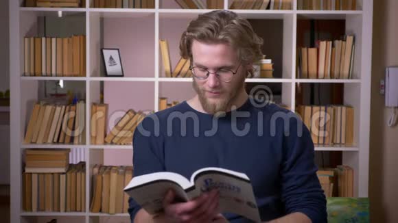 在大学里一位有魅力的男大学生正在看书看着摄像机开心地笑着视频的预览图