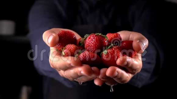 草莓从人的手黑暗的背景缓慢地烹饪视频的预览图