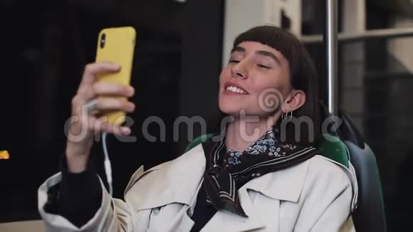 年轻的微笑女子在乘坐公共交通工具时有一个视频电话城市灯光背景视频的预览图