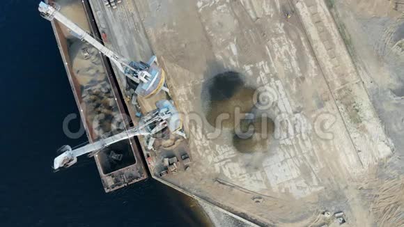 港口起重机工作卸下一艘装满碎石的大驳船视频的预览图