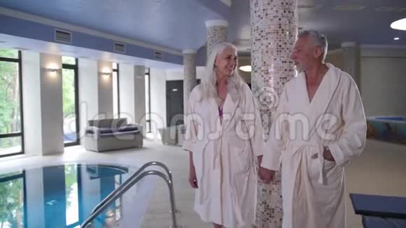 成熟的夫妻手牵手走到酒店游泳池视频的预览图