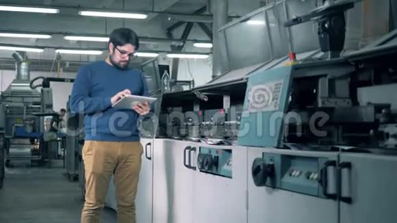 男性专家正在观察一台造纸机的工作过程视频的预览图