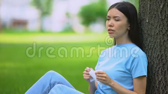 年轻女子打喷嚏坐在树上患有春季过敏症药物视频的预览图