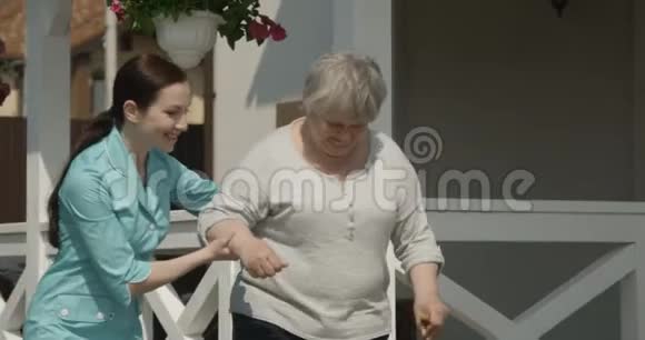 护士在养老院帮助老人散步快乐的老人在阳光明媚的日子微笑红镜头视频的预览图