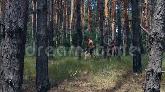 雄性和雌性野蛮人在树林里打猎手里拿着武器4k视频的预览图