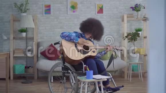 残疾的非裔美国妇女她留着非洲发型坐在轮椅上弹声吉他视频的预览图