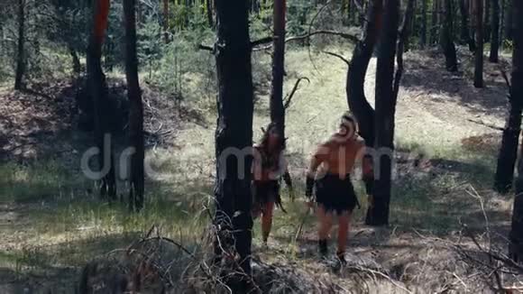 野蛮的猎人们手里拿着斧子和剑在树林里行走视频的预览图