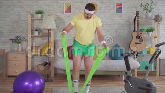 有趣的男人失败者在家锻炼健身用橡皮筋慢动作视频的预览图