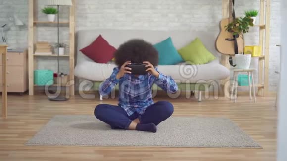 表现积极的非洲裔美国年轻女性在客厅里使用VR眼镜和虚拟技术的肖像视频的预览图
