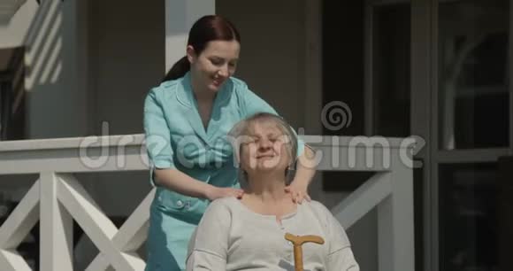 理疗师在医院康复中心户外用红相机拍摄的阳光日镜头按摩老年妇女视频的预览图