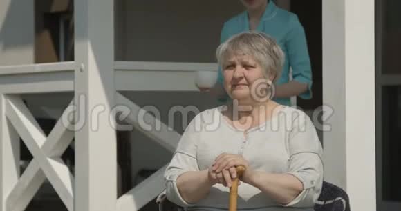 在红镜头拍摄的阳光明媚的日子里养老院护理员为快乐的养老金领取者一起笑一杯咖啡视频的预览图