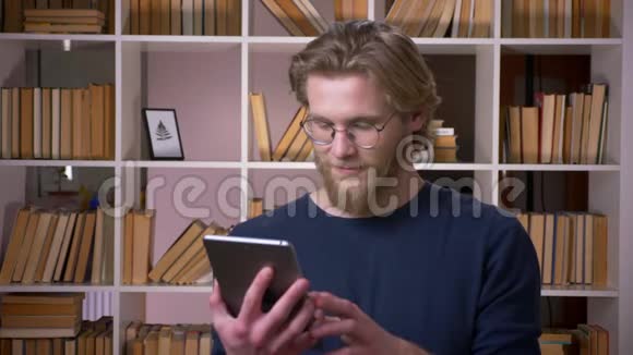 用平板电脑拍摄成年魅力男学生的特写镜头在大学里用绿色屏幕拍摄视频的预览图
