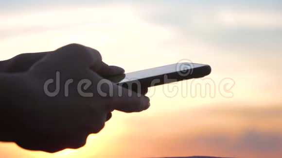 日落时使用智能手机的女人落日余晖黄金时刻视频的预览图