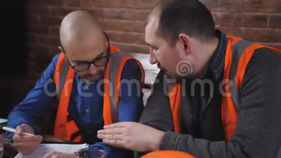 两名工程师在午休时间在一张桌子上喝咖啡讨论操作问题视频的预览图