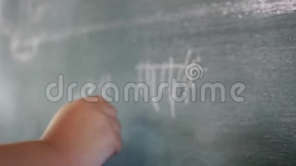 一个可爱的小女孩在学校用白色粉笔在黑板上画画视频的预览图
