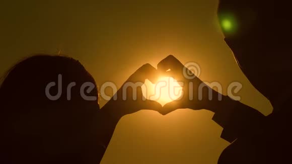 一对相爱的夫妇的剪影在明亮的阳光下显示了一种心灵的象征太阳在手里恋人的共同工作视频的预览图