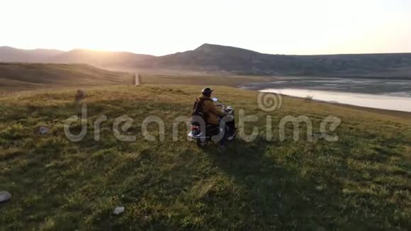 摄像机在旅行者身边旋转骑着一辆脚踏车他爬上山顶享受着夕阳的照耀视频的预览图