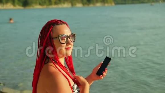 日落时分年轻的晒黑了的女人在湖边远程工作视频的预览图