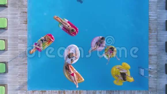 在夏季游泳池放松与女性朋友愉快地一起在昂贵的泳池边的充气戒指和床垫上游泳视频的预览图