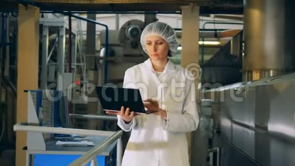 一位穿着制服带着笔记本电脑的女士正沿着工厂走着视频的预览图
