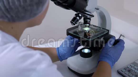 无法辨认的女性实验室技术人员进行医学测试使用显微镜视频的预览图