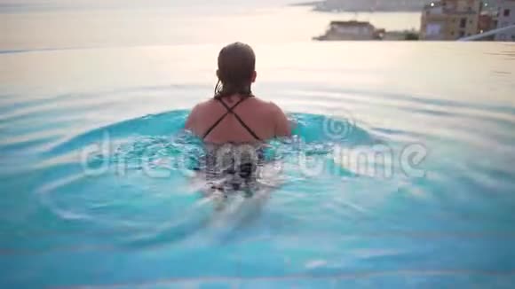 女人在游泳池水疗享受日落在海上豪华度假旅行在希腊欧洲穿比基尼的女孩视频的预览图