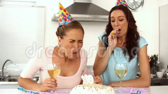 女人一边吹蜡烛一边和朋友庆祝生日视频的预览图