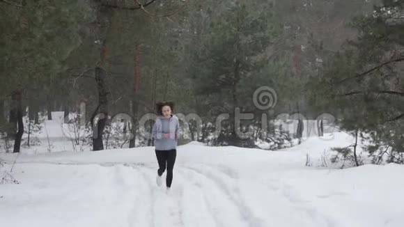 小径跑年轻迷人的白种人女孩在雪地上奔跑在森林里前面跟射弹视频的预览图