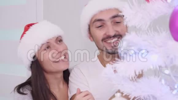 在圣诞树旁微笑着拥抱着一对快乐的夫妇享受着寒假的时光视频的预览图