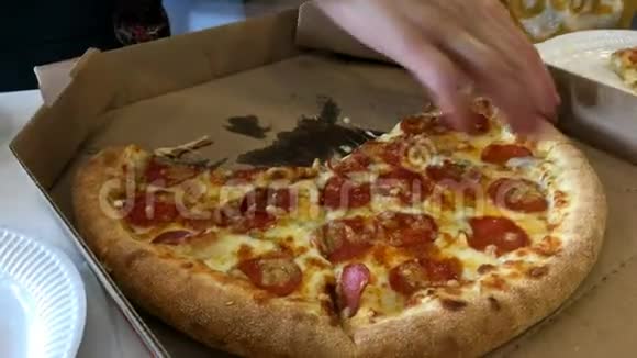 人的手从盒子里撕下一片热的新鲜披萨放在纸盘上视频的预览图