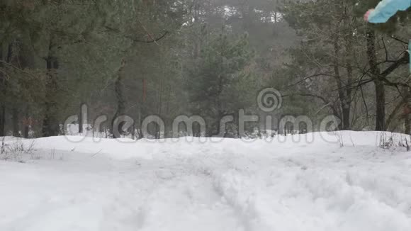 小径跑白种人老女人在雪地上奔跑在森林里后退静态镜头视频的预览图