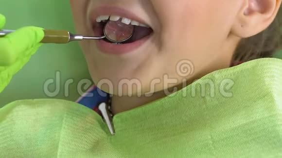 兴奋的孩子坐在牙科椅上医生用特殊的镜子检查牙齿视频的预览图