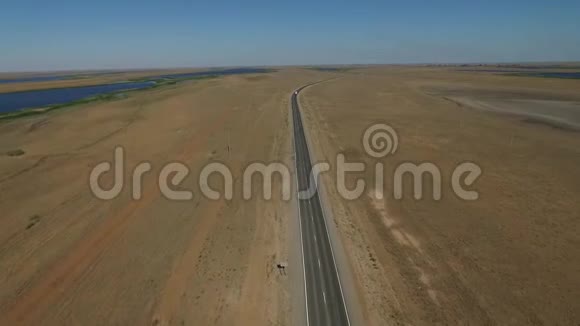 在沙漠中的空旷道路上鸟瞰或在茫茫人海中的田野上鸟瞰两车道高速公路的电影镜头视频的预览图