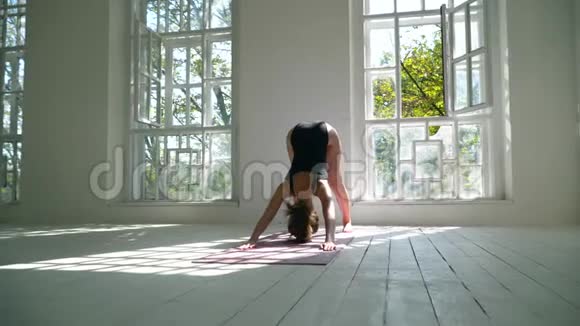 红发年轻健康的白种人女人站在白色的大房间里的垫子上练习瑜伽年轻女子视频的预览图