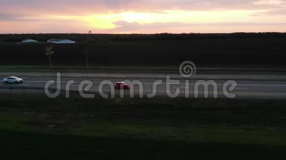日落或日出时红色的小型复古汽车在4车道高速公路上行驶并有转向灯视频的预览图