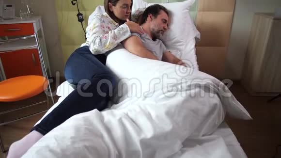 爱悲伤的女人抚摸着睡在诊所里的丈夫视频的预览图