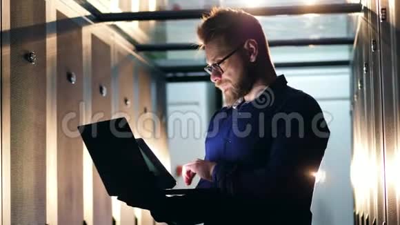 男工程师IT专家与笔记本电脑合作站在服务器机房视频的预览图