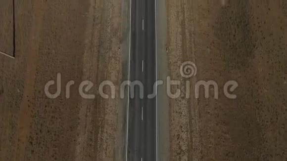 在沙漠中的空旷道路上鸟瞰或在茫茫人海中的田野上鸟瞰两车道高速公路的电影镜头视频的预览图