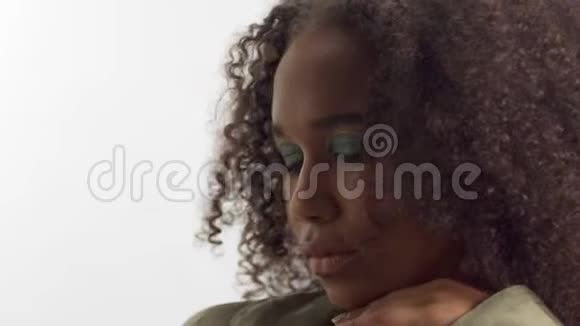 年轻的混血模特留着卷发的白色工作室亮绿色的眼妆视频的预览图