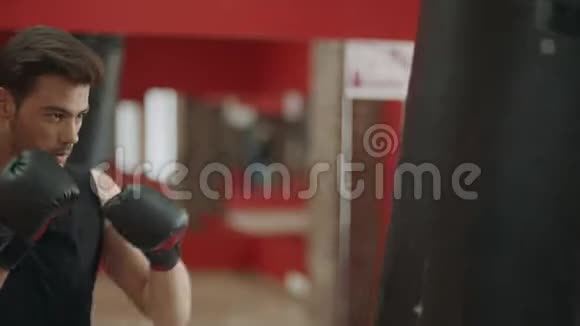 健身男子训练箱踢在体育俱乐部拳击手在手套里踢拳击袋视频的预览图