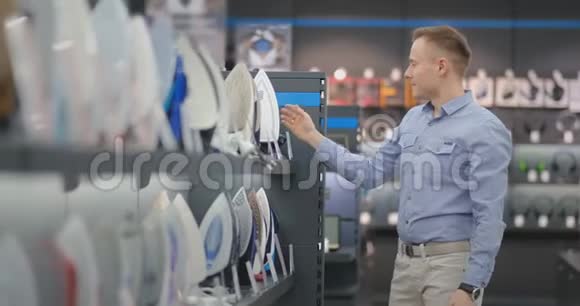 一个年轻英俊的男人在商店里检查熨斗来买新房子智能科技铁的选择视频的预览图