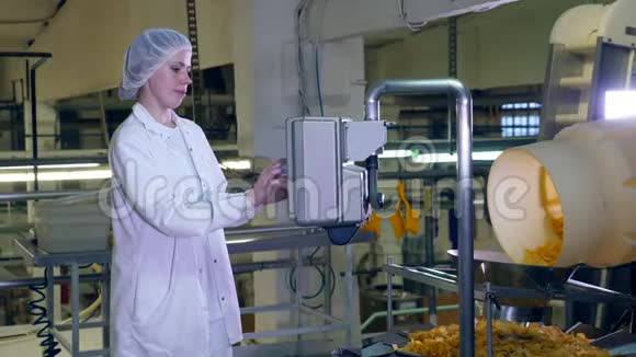 女工人站在一个食品设施里控制着一个带薯片的传送带视频的预览图