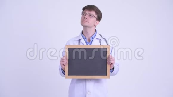 快乐的年轻英俊的医生一边拿着黑板一边思考视频的预览图