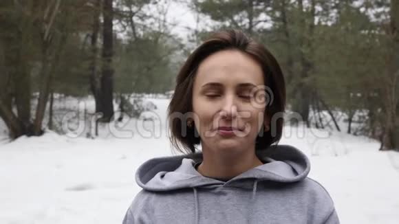 年轻迷人的白人女孩在冬天在雪地公园跑步之前先戴上耳机关闭前镜头慢动作视频的预览图