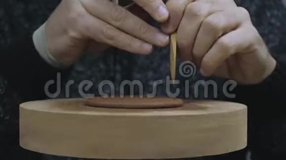 一个陶土师傅用木刀割掉一个均匀的陶土圈为宜兴陶土的茶壶盖上盖子手工粘土视频的预览图