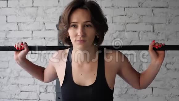 这段视频是关于美丽的年轻运动女性做背部蹲式有氧运动在健身房前方近景视频的预览图