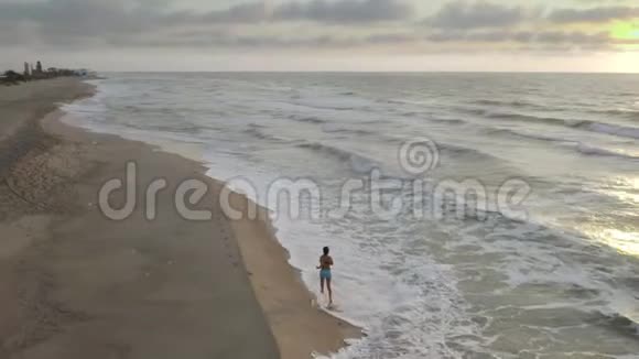 日落时分在海滩上慢跑的女人美丽的云彩和令人叹为观止的日落视频的预览图