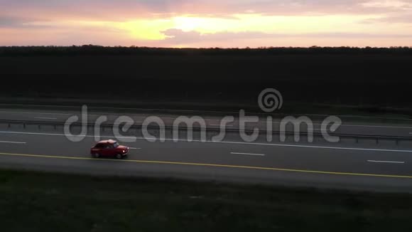 日落或日出时红色的小型复古汽车在4车道高速公路上行驶并有转向灯视频的预览图