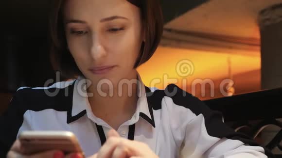 年轻迷人的女人在一家舒适的咖啡馆里使用她的手机她微笑而快乐视频的预览图