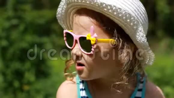 一个戴着帽子和太阳镜的快乐孩子的特写肖像笑着笑着视频的预览图